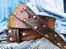 Brown leather belt with two shades of brown two pieces on the front and storage for guitar pick with bronze studs around the belt