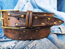 Brown leather belt with two shades of brown two pieces on the front and storage for guitar pick with bronze studs around the belt