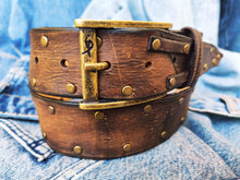 Brown leather belt with two shades of brown two pieces on the front and storage for guitar pick with bronze studs around the belt