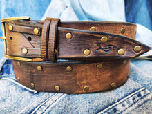 Brown leather belt with two shades of brown two pieces on the front and storage for guitar pick with bronze studs around the belt