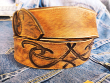 A brown leather belt with tribal that made from ishaor logo and vintage finish that give to the belt western rodeo style