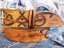 A brown leather belt with tribal that made from ishaor logo and vintage finish that give to the belt western rodeo style